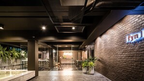 A modern lobby with a brick wall, a reception desk, and potted plants. - Fyn Hotel (Bangkok)