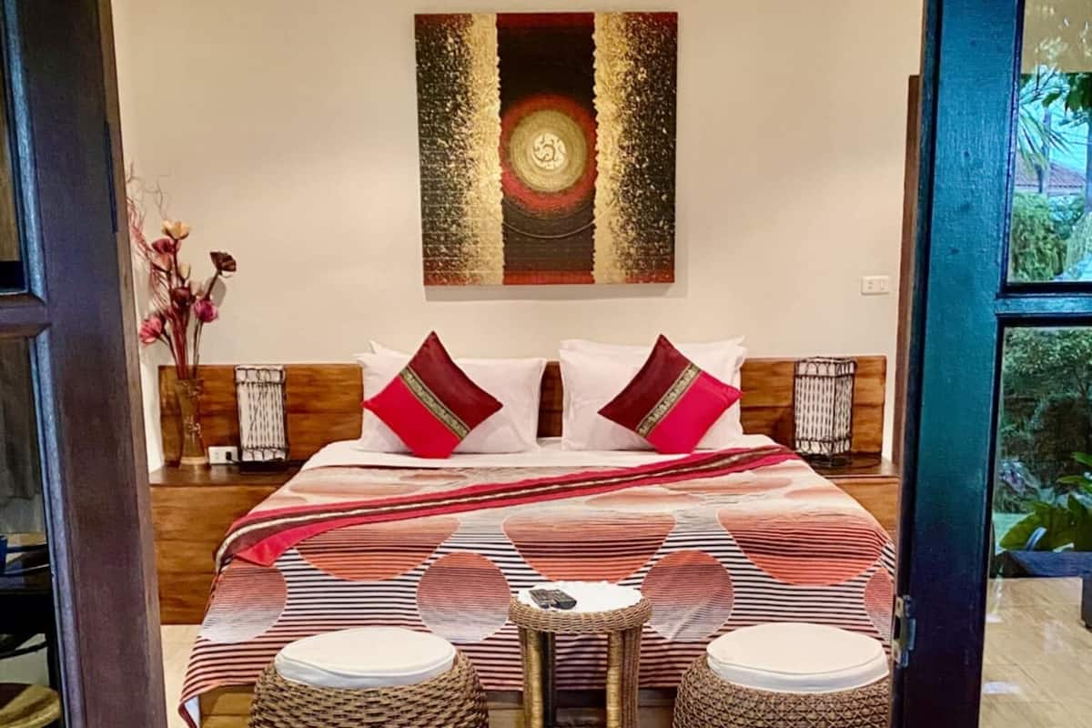 A bedroom with a large bed, two side tables, and a wall-mounted artwork.