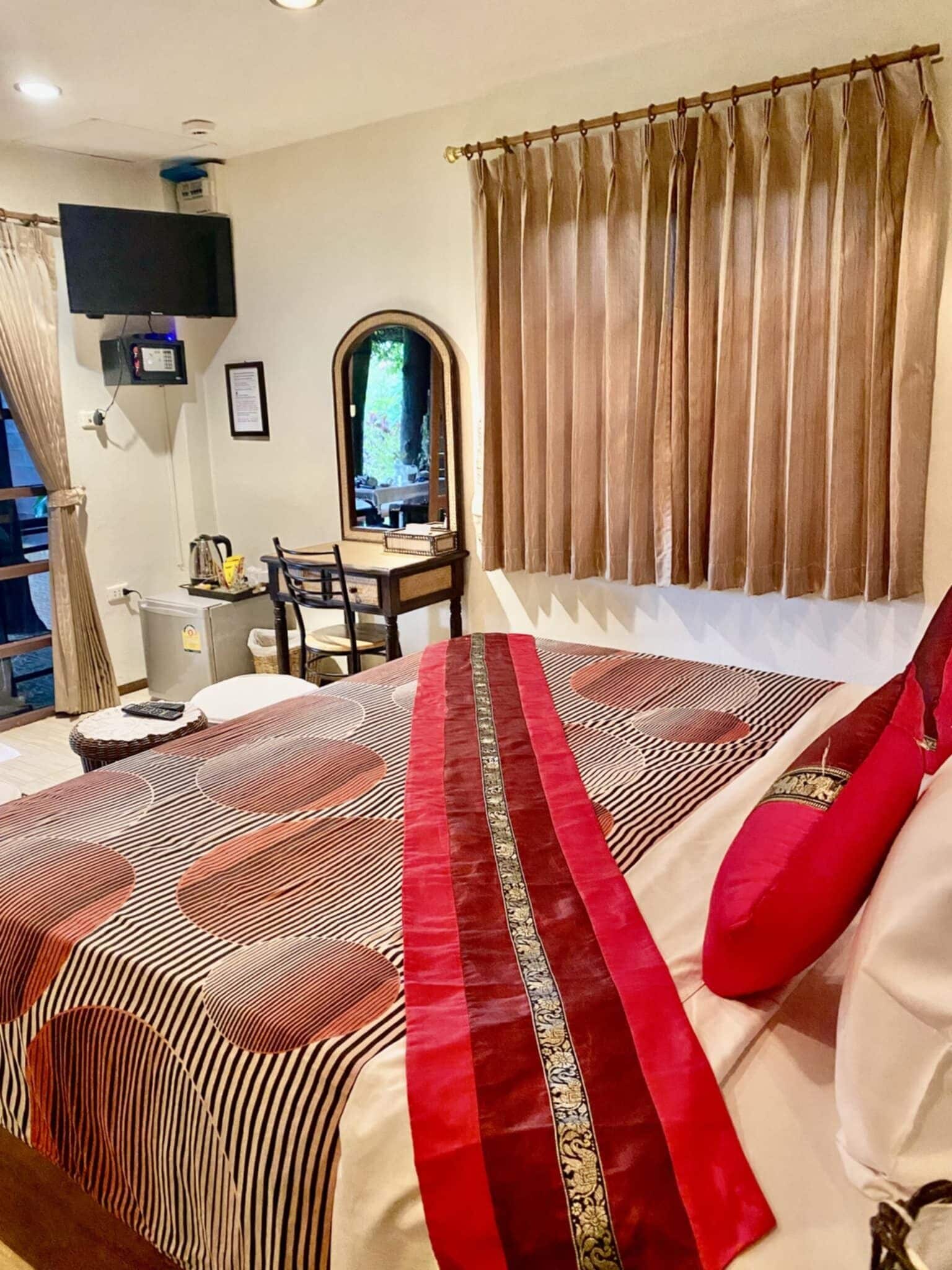 A hotel room with a bed, a desk, a chair, a television, and a window with curtains.