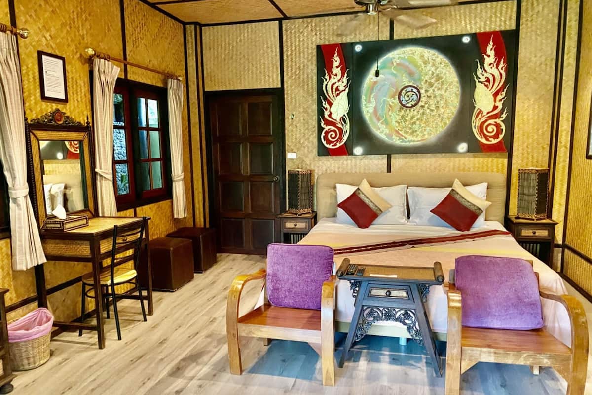 A traditional room with a bed, two wooden chairs, a desk, and a mirror.