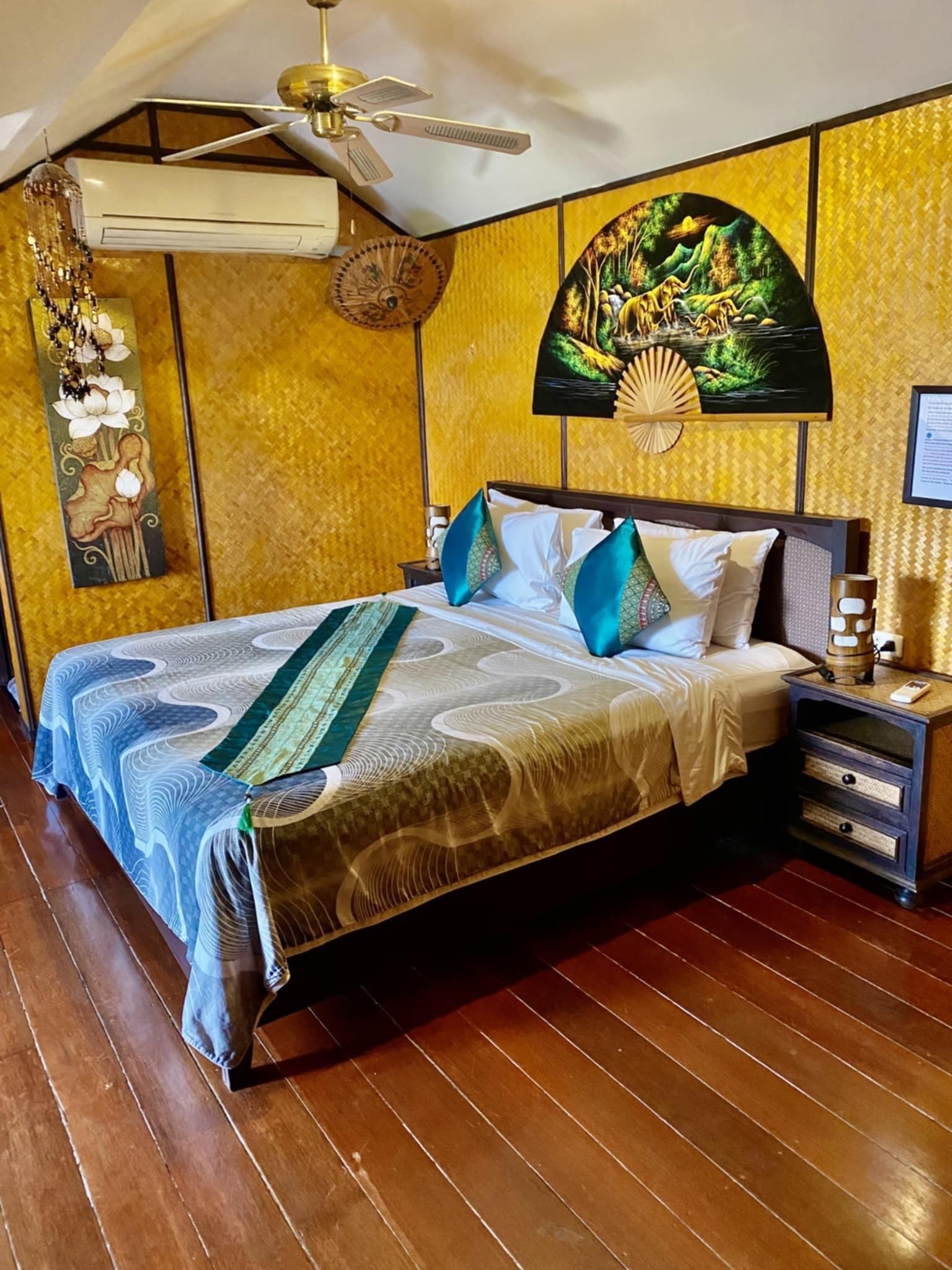 A hotel room with a bed, a nightstand, a ceiling fan, and a wall-mounted air conditioner.