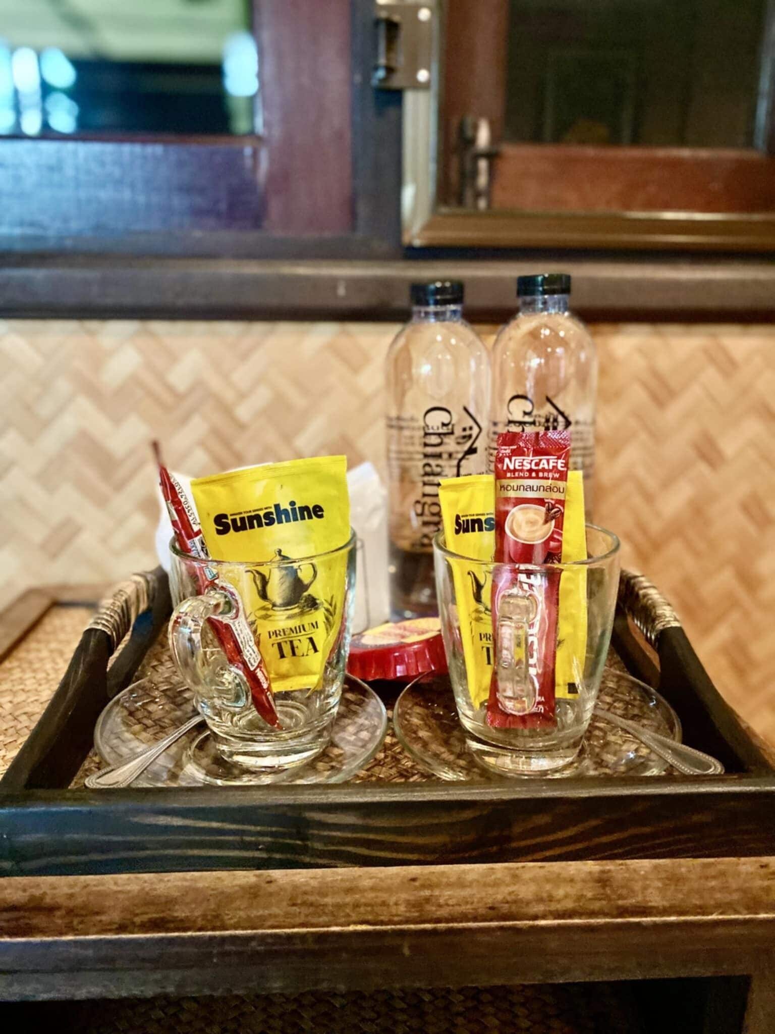 A tray with two glasses containing Sunrise tea packets and a bottle of Chai.