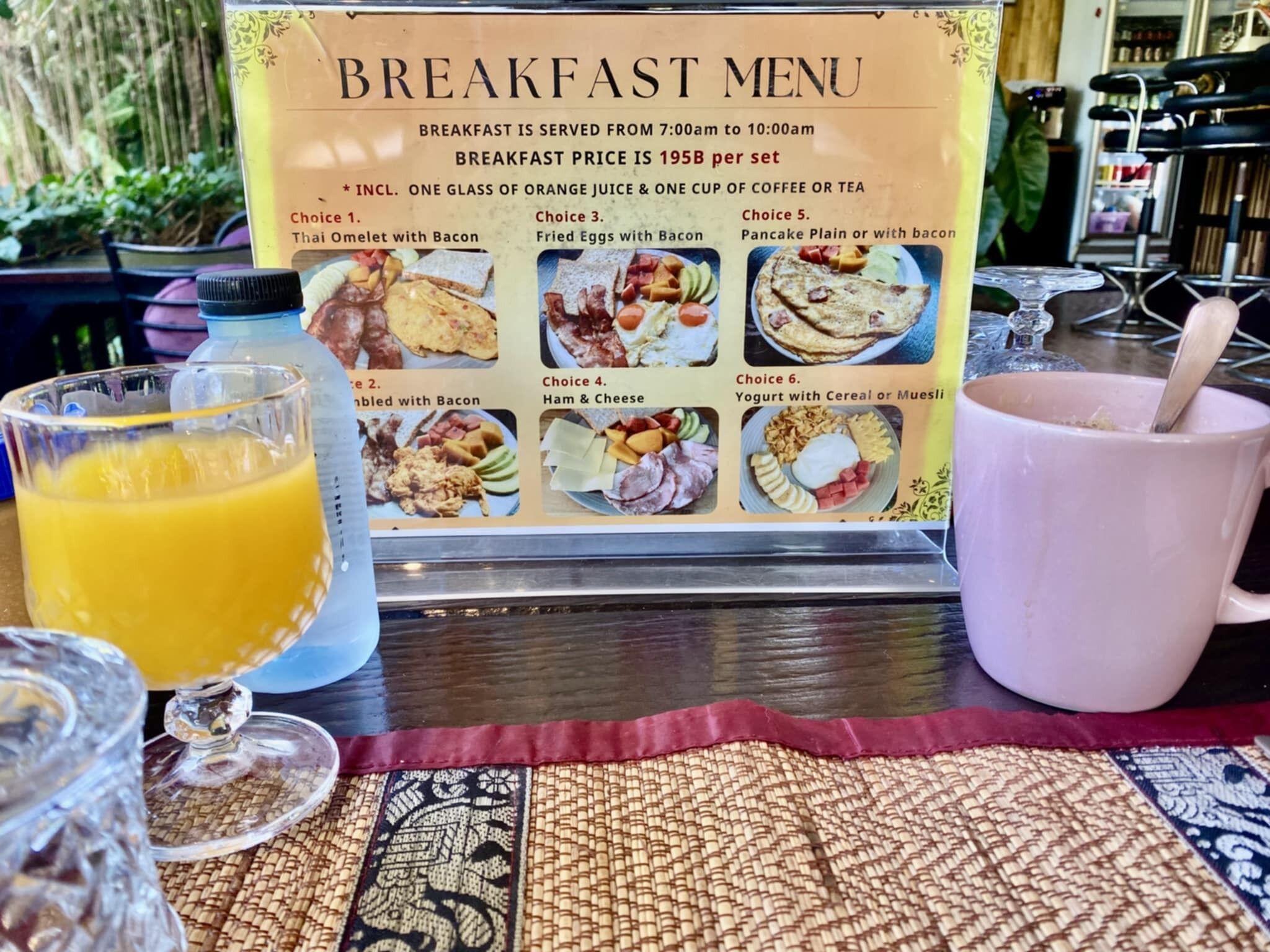 Un menú de desayuno con diversas opciones de comida y un vaso de jugo de naranja.