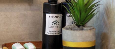 Two bottles of Jade Green hotel shampoo, a potted plant, and a tray with two soap bars.