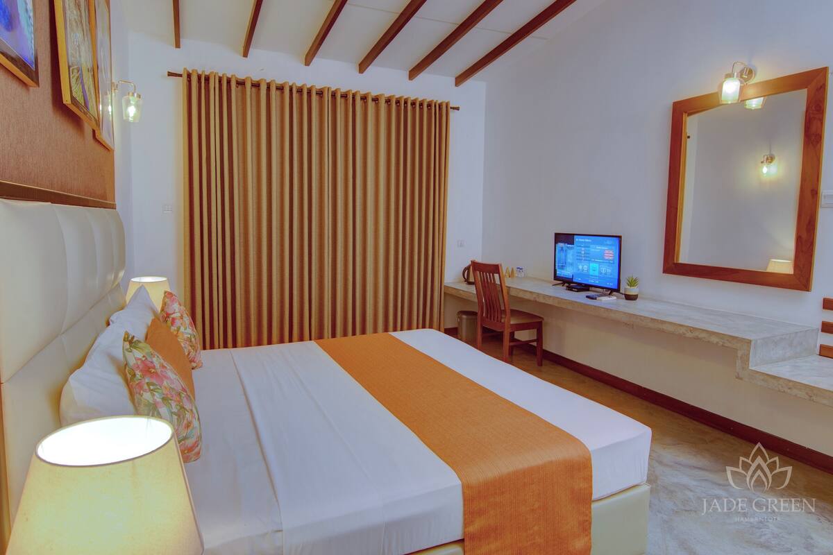 Une chambre d’hôtel avec un lit, un bureau équipé d’un ordinateur, une chaise et un grand miroir.