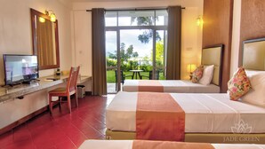 Una habitación de hotel con dos camas, un escritorio y televisor, y vistas al exterior.