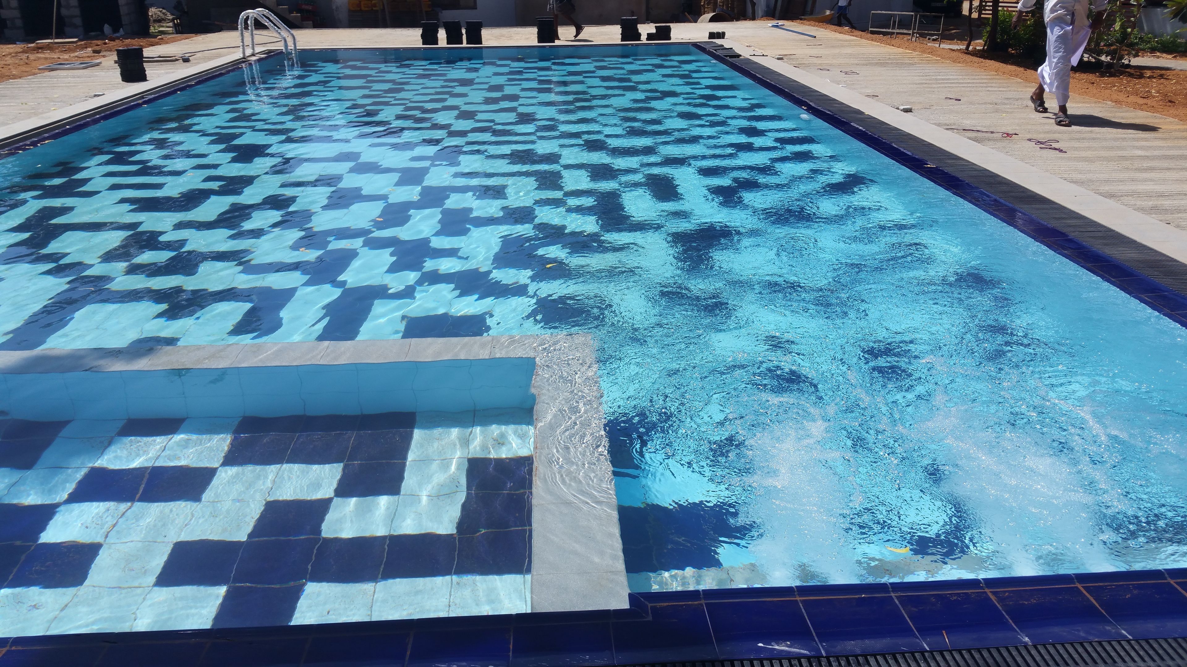Une piscine dont le fond est recouvert de carreaux disposés en motif à damier.