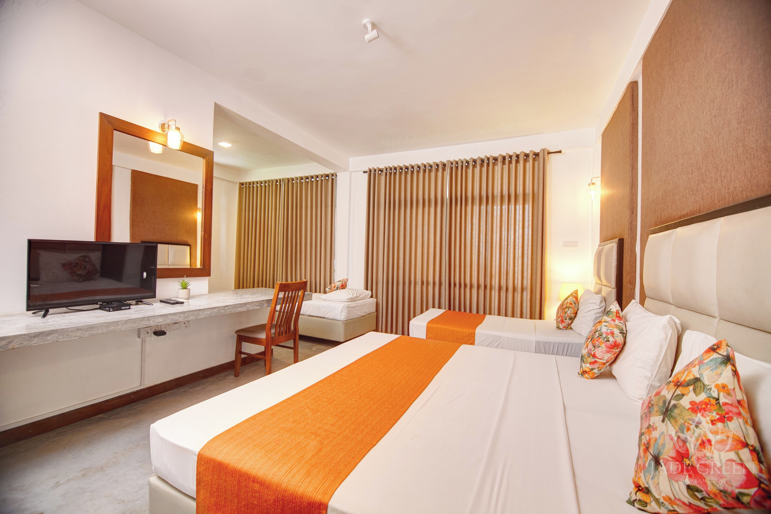 A hotel room with a bed, a desk, a chair, a television, and curtains.