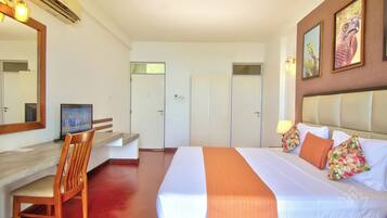 Een hotelkamer met een bed, een bureau met stoel, een garderobe en een spiegel.