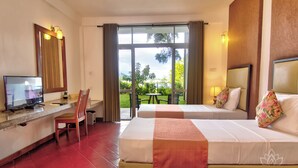 Une chambre d’hôtel avec deux lits, un bureau avec une télévision et une vue sur l’extérieur.