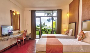 Una habitación de hotel con dos camas, un escritorio y televisor, y vistas al exterior.