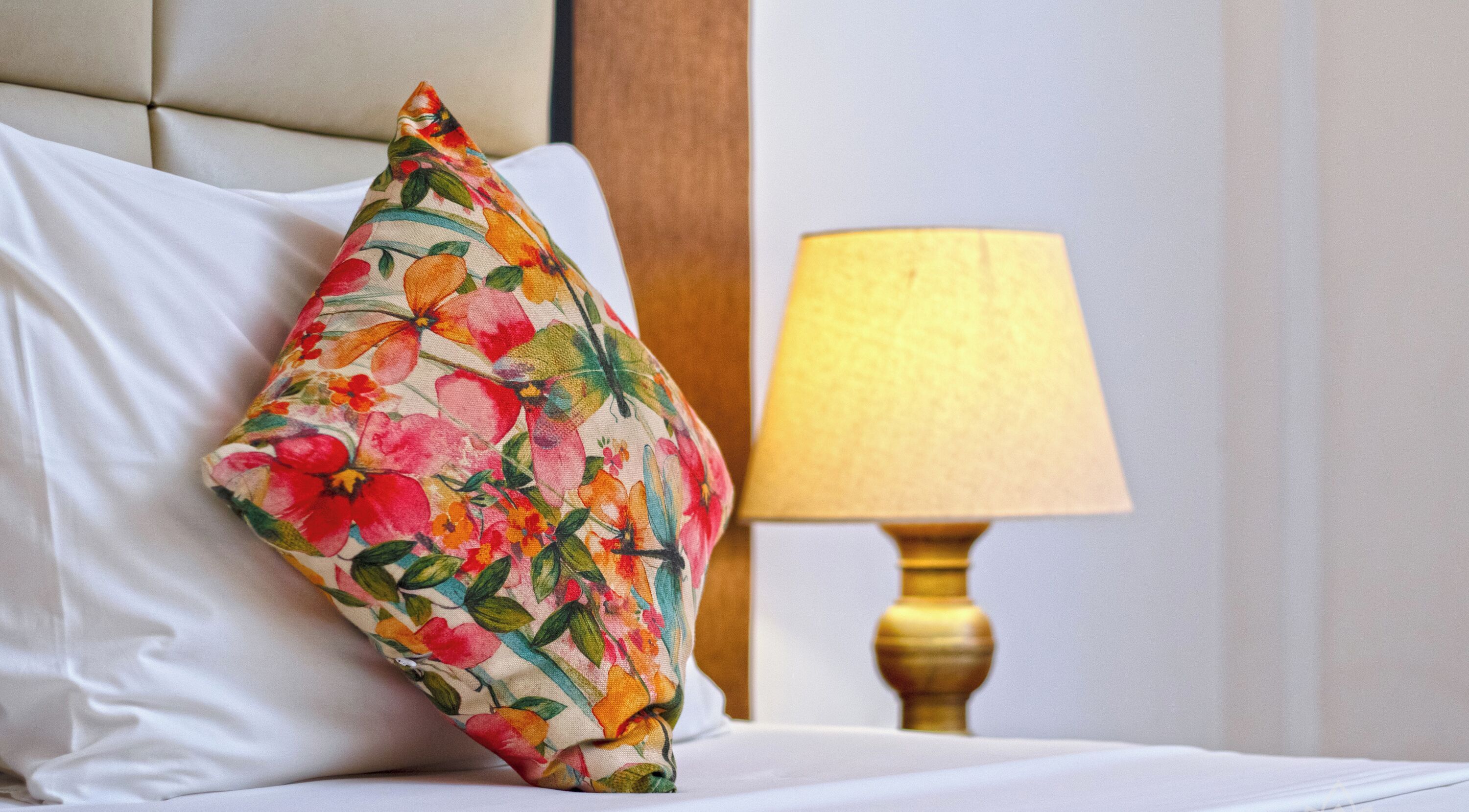 Un lit avec un coussin à motifs floraux et une lampe de chevet.