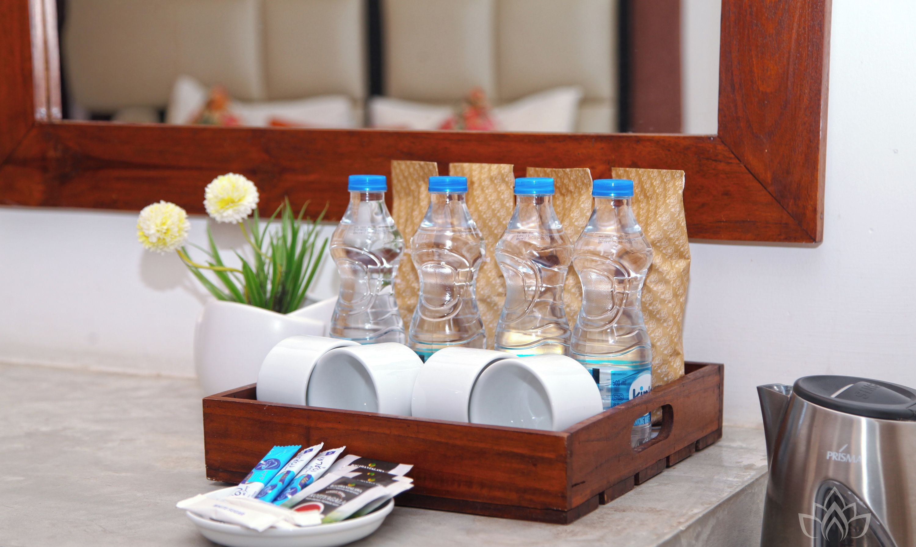 Un plateau contenant des bouteilles d’eau, des tasses à café et des sachets de thé, posé sur le comptoir d’un hôtel.