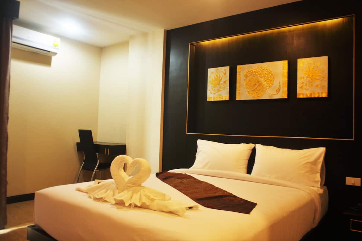A hotel room with a neatly made bed, a desk, and three wall-mounted artworks.