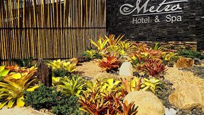 A hotel entrance with a bamboo fence and a sign that reads "Metro Hotel & Spa". - Metro Hotel & Spa (Thung Song)