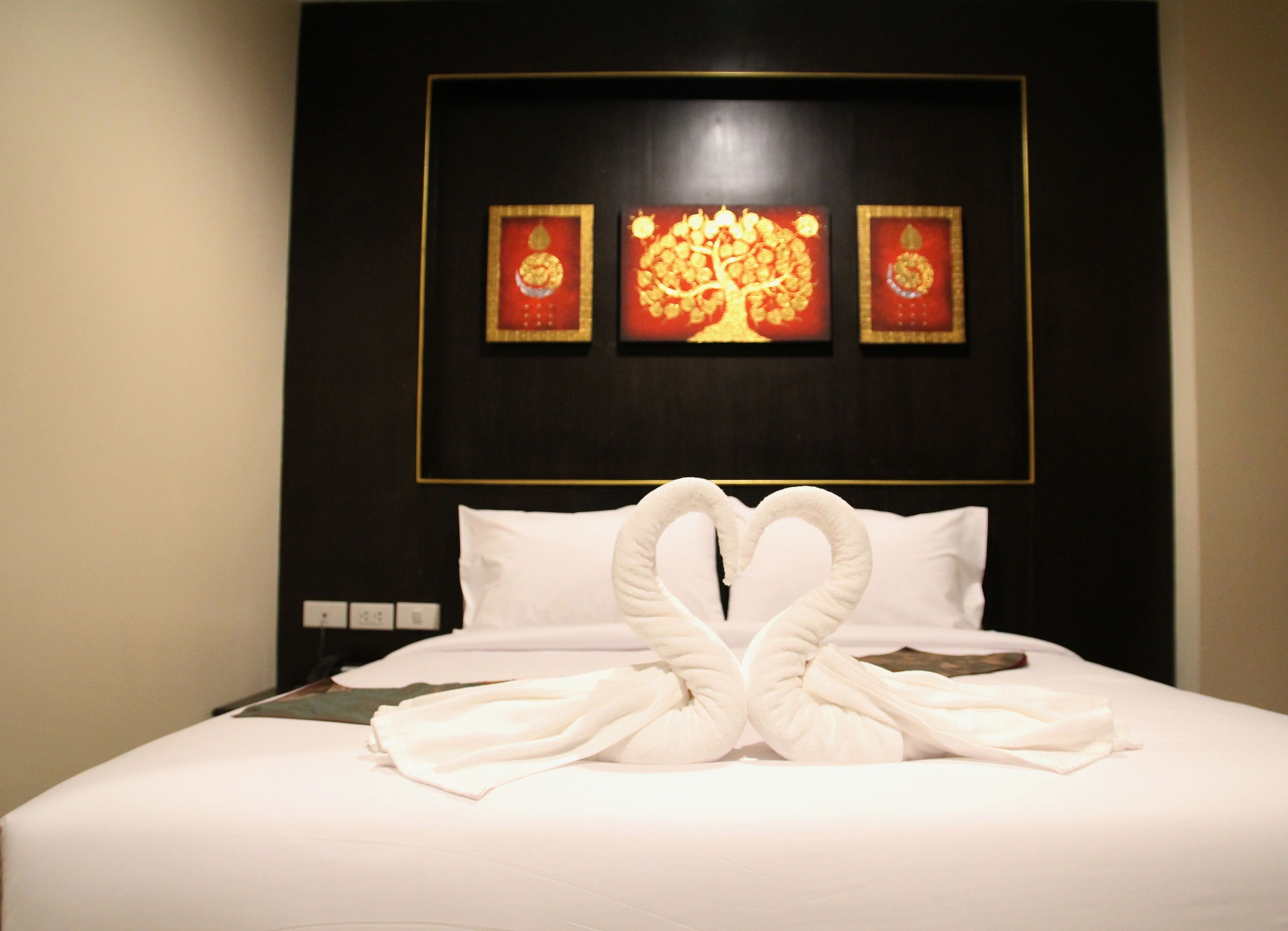 A hotel room with a neatly made bed, a wall-mounted artwork, and a power outlet.