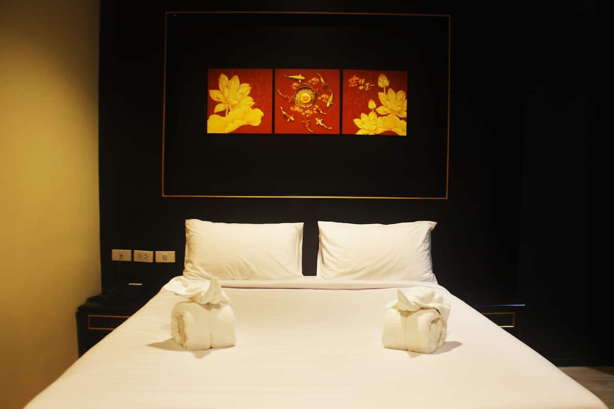 A neatly made bed with white linens and two towels folded at the foot.