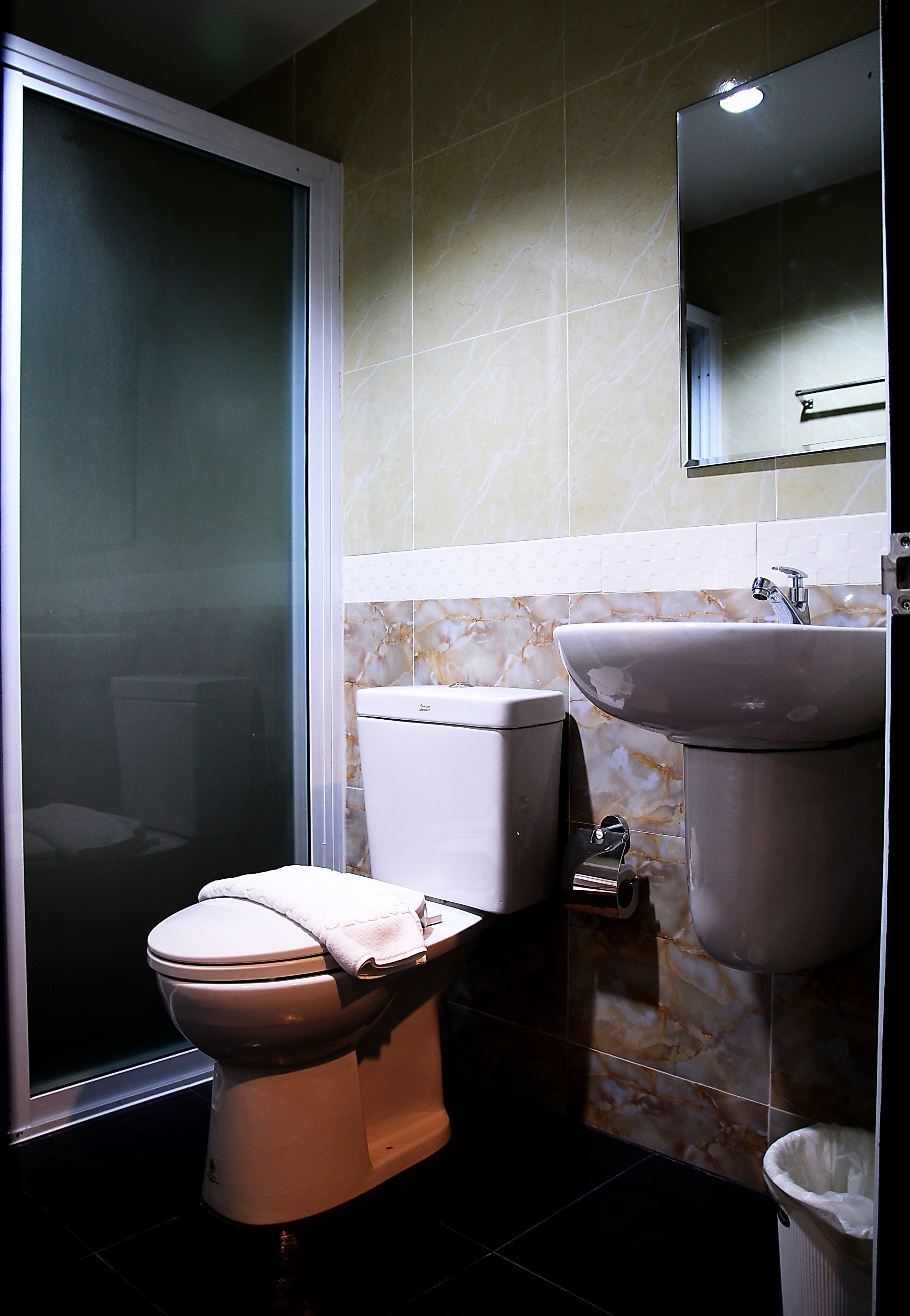 Un baño con inodoro, lavamanos y espejo.