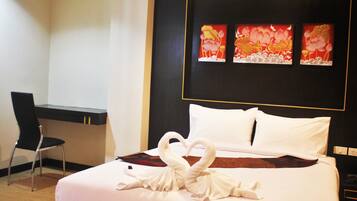 A hotel room with a bed, a desk, and a chair. There are three paintings on the wall above the bed.