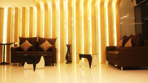 A modern lobby with a sofa, a small table, and a decorative vase. - Metro Hotel & Spa (Thung Song)