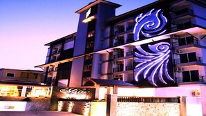 A multi-story hotel with a prominent illuminated sign and a gated entrance. - Metro Hotel & Spa (Thung Song)