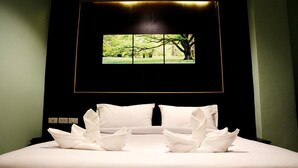 A hotel room with a bed, white pillows, and a large window displaying a tree. - Metro Hotel & Spa (Thung Song)