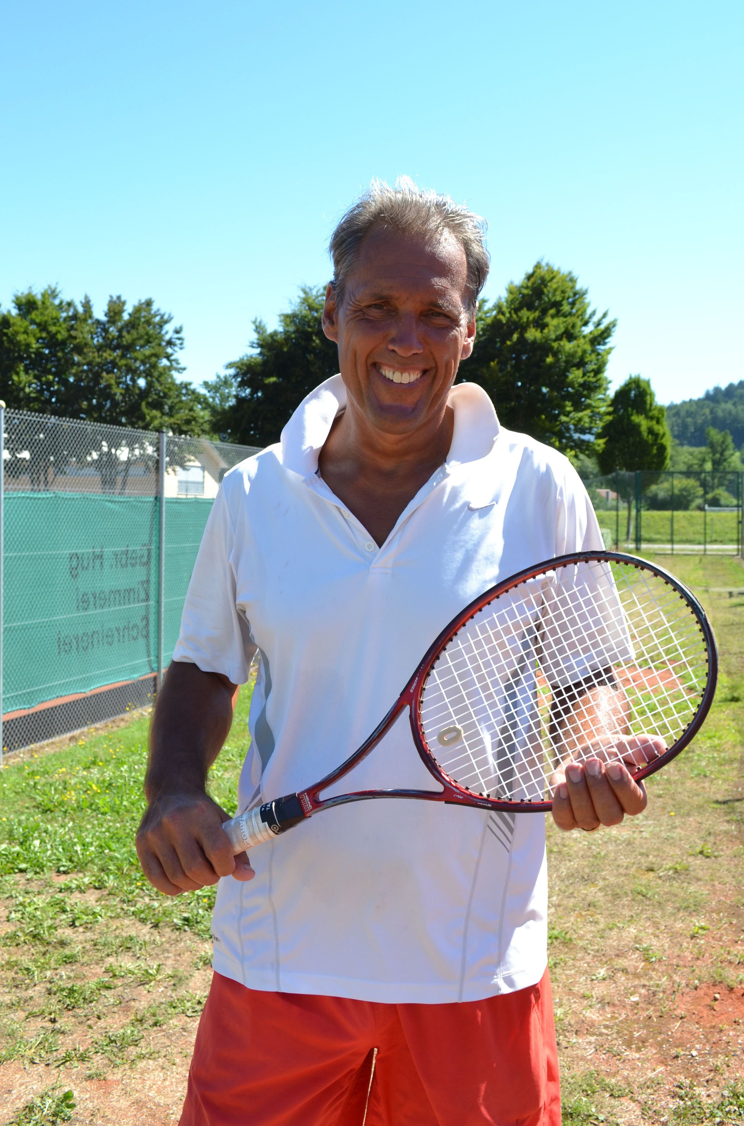 A person holding a tennis racket outdoors.