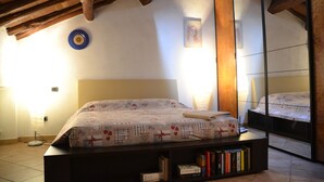 Une chambre à coucher avec un lit, une bibliothèque, un miroir et une lampe.