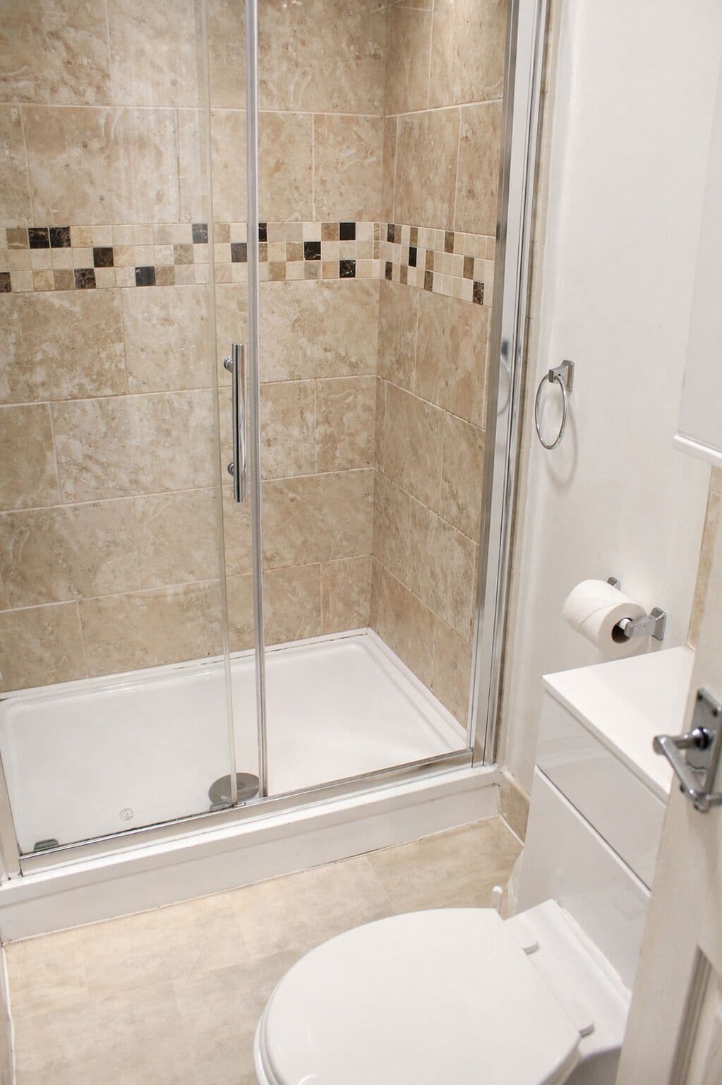 A bathroom with a glass-enclosed shower, a toilet, and a sink.