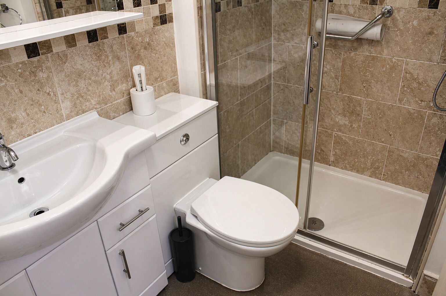 Et badeværelse med vask, toilet og bruser.