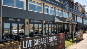 A building with a sign for 'LIVE CABARET SHOWS WORLD CLASS ENTERTAINERS' and a 'BAR & RESTAURANT OPEN TO NON-RESIDENTS' sign.
