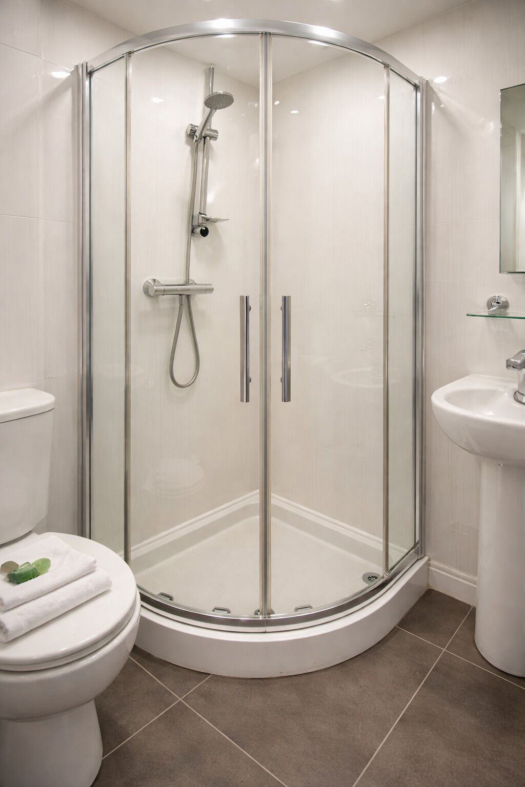 A modern bathroom with a glass-enclosed shower, a toilet, and a sink.