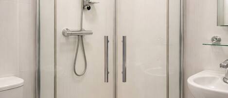 Un baño moderno con ducha de vidrio, inodoro y lavamanos.