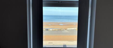 A window with a view of a beach and a fence.