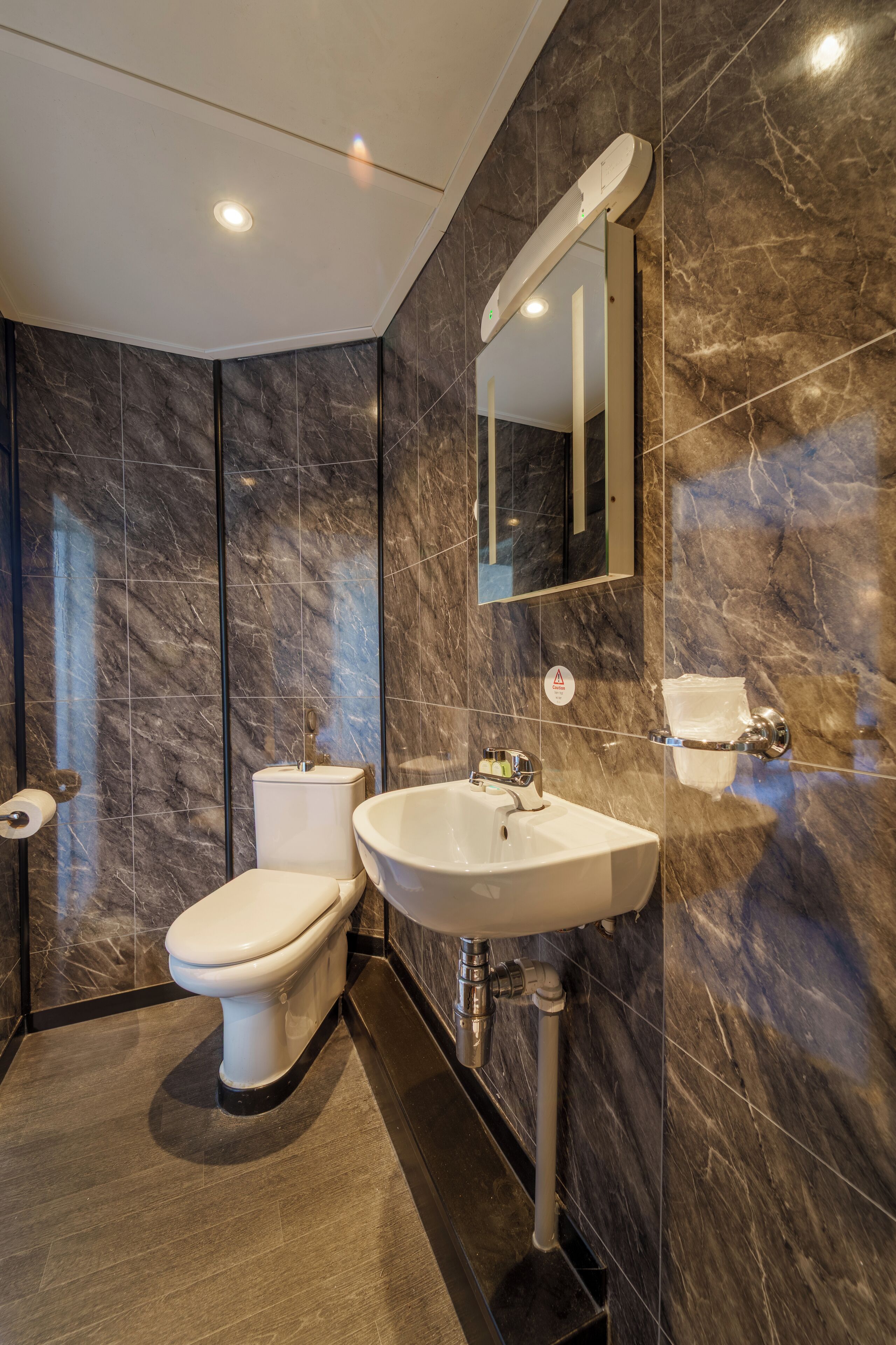 A modern bathroom with a toilet, sink, and mirror.