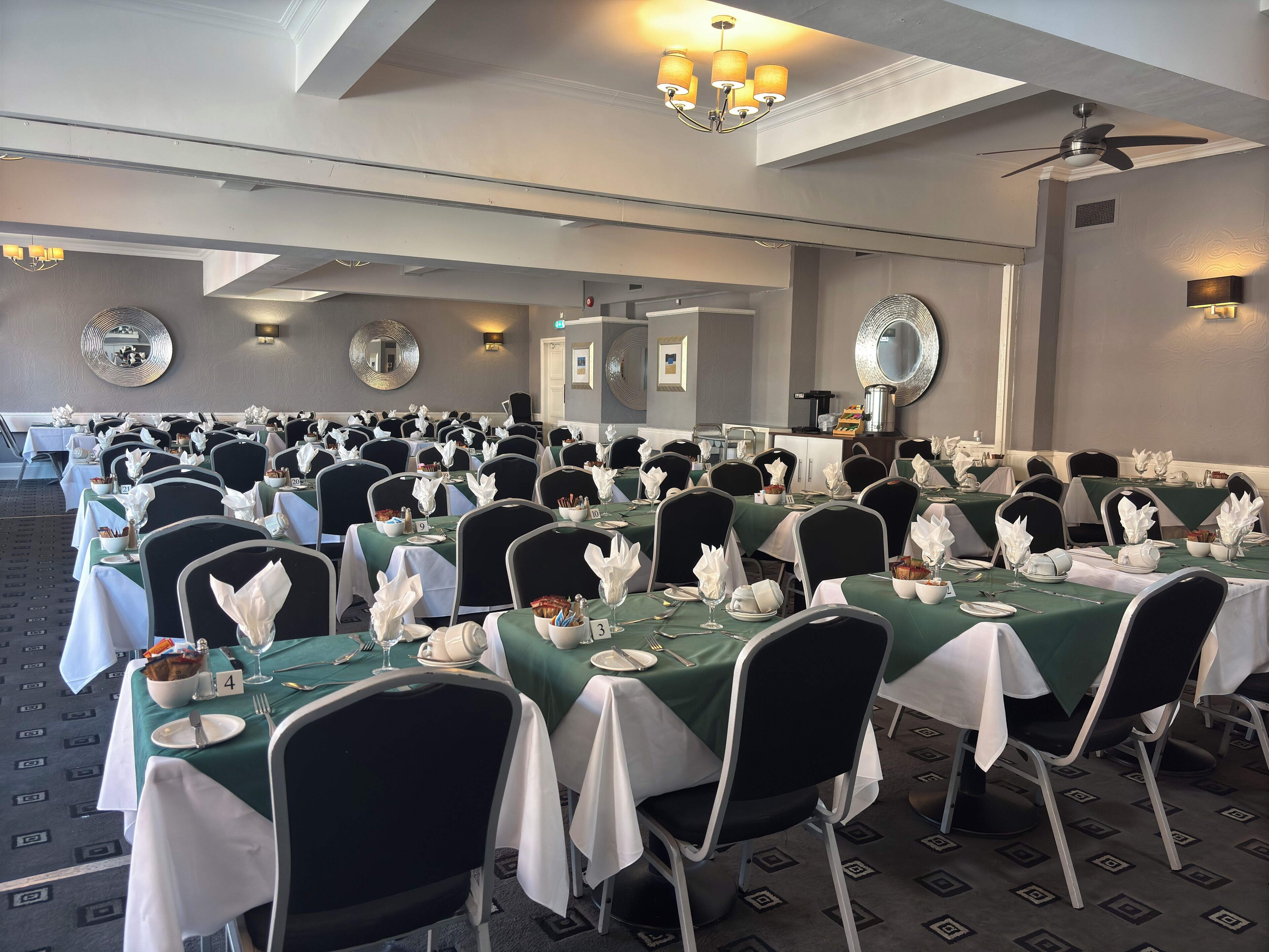 En festvogn med rækker af borde dækket op til en formel begivenhed, med stole, dug og servise.