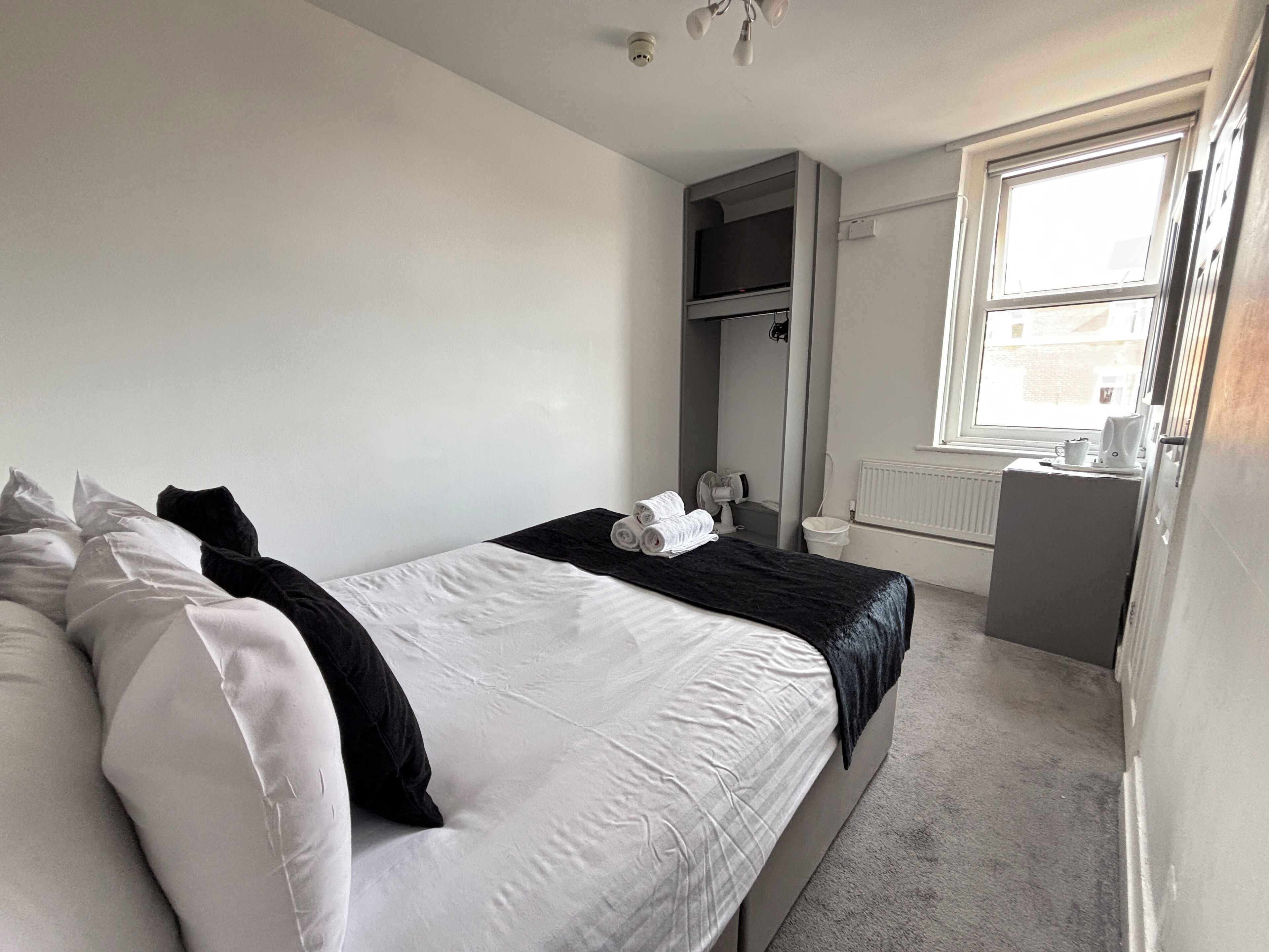 A bedroom with a bed, a dresser, a mirror, a radiator, and a window.