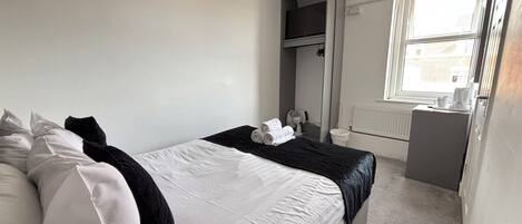 A bedroom with a bed, a dresser, a mirror, a radiator, and a window.