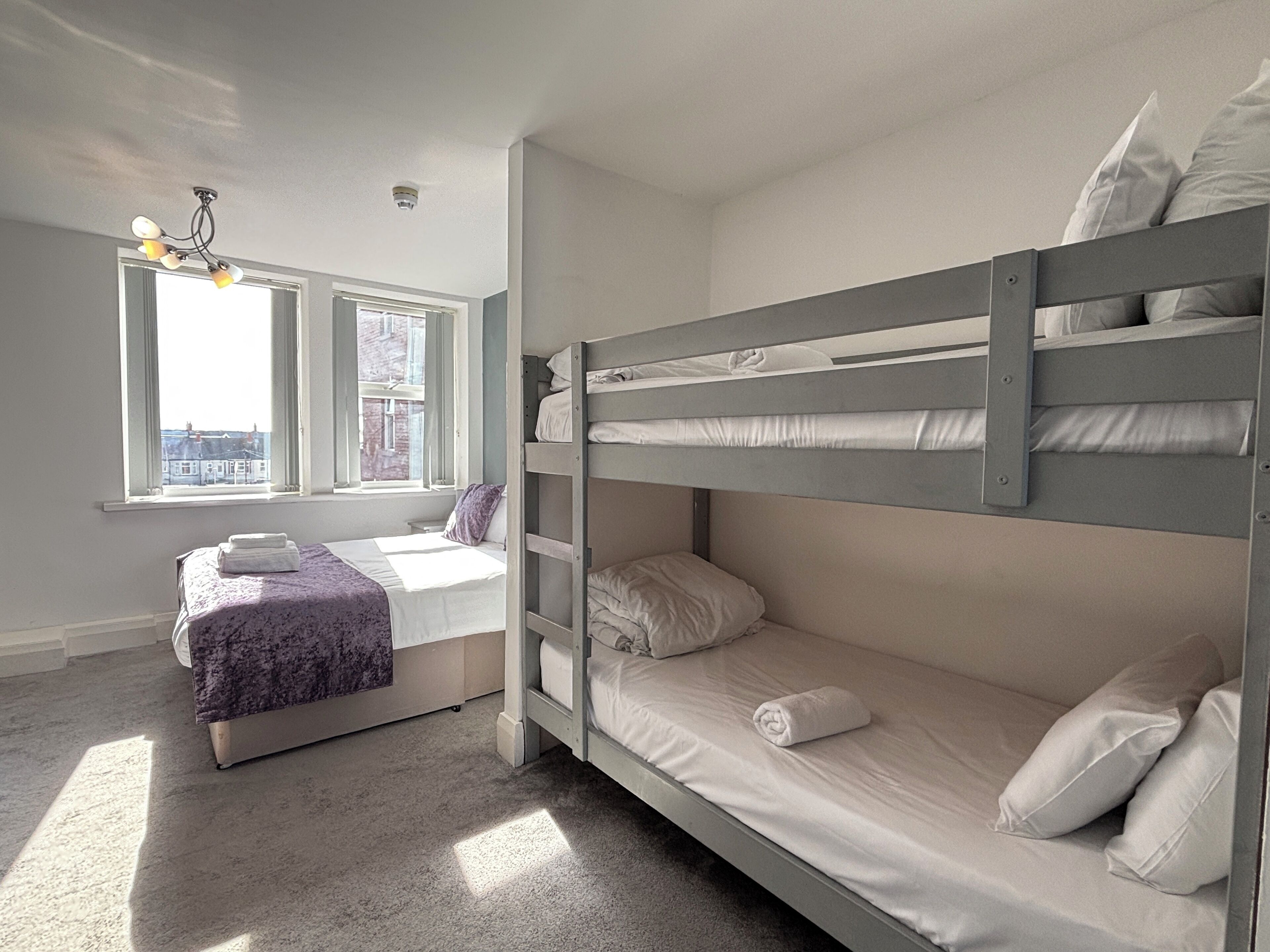 Una habitación con literas, una ventana con vistas y una lámpara en el techo.