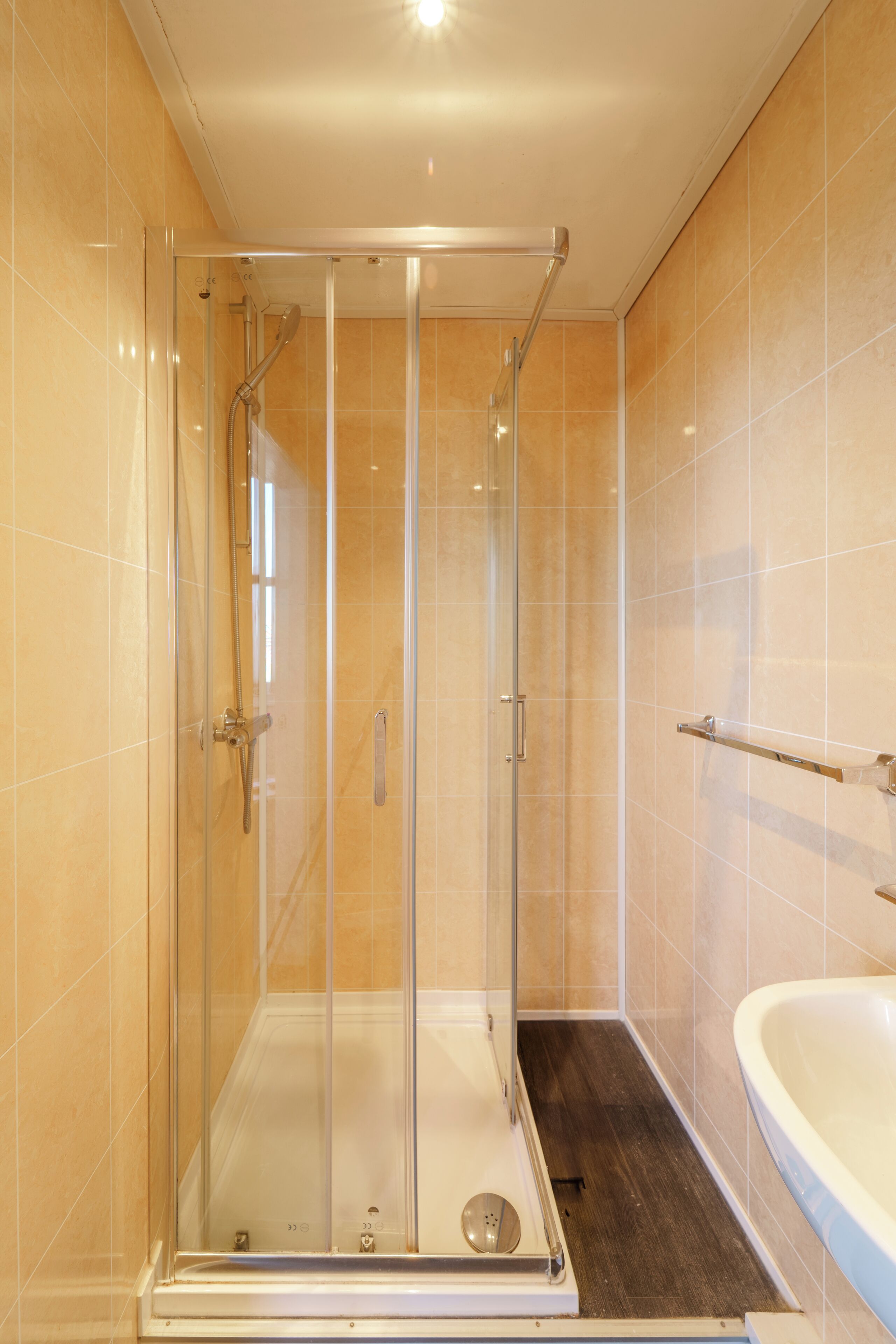 A glass-enclosed shower with a white bathtub and a towel rack.