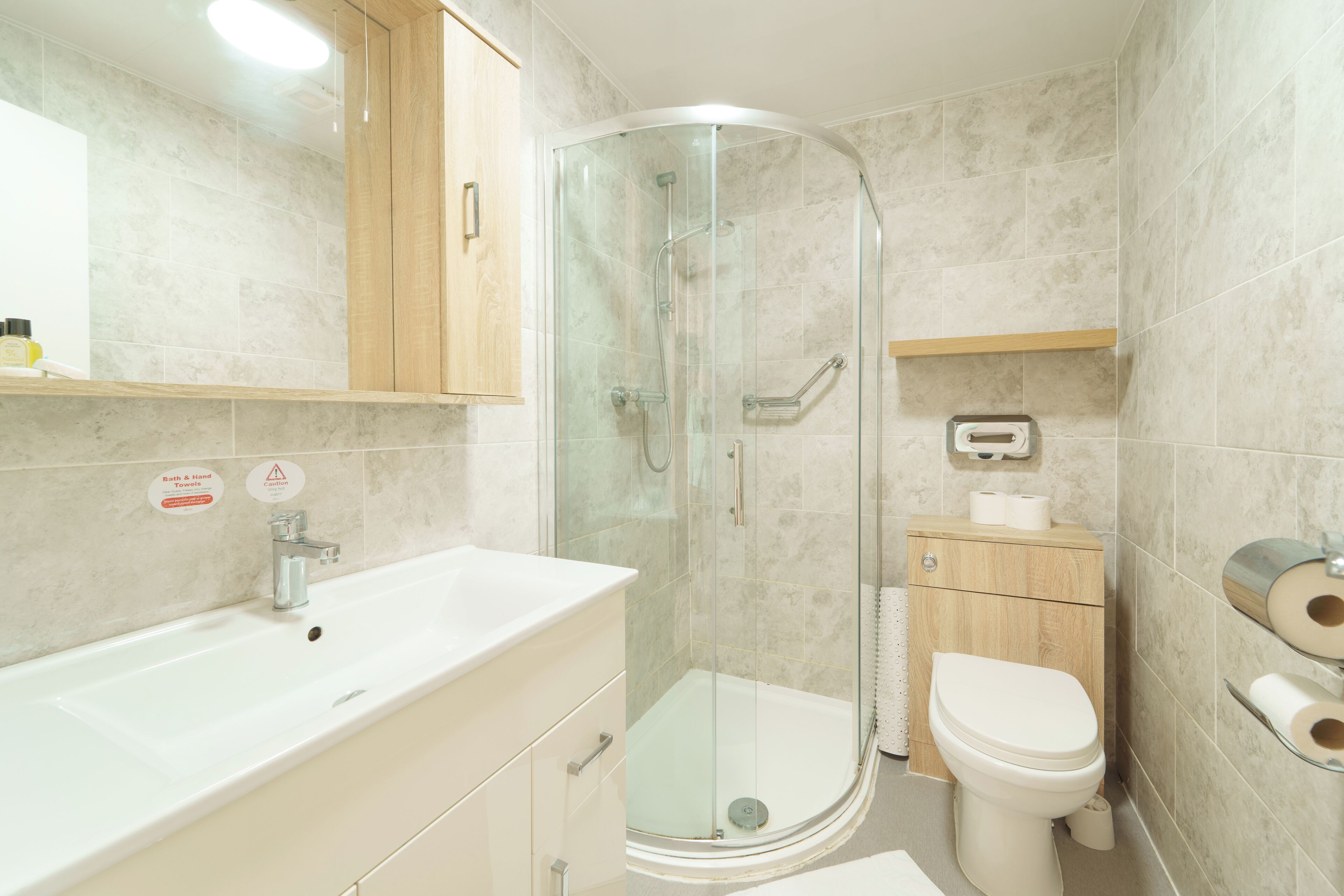 Een moderne badkamer met een douchecabine van glas, een witte wastafel en een toilet.