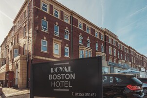 Een bord voor het Royal Boston Hotel, met een klassiek bakstenen gebouw op de achtergrond.