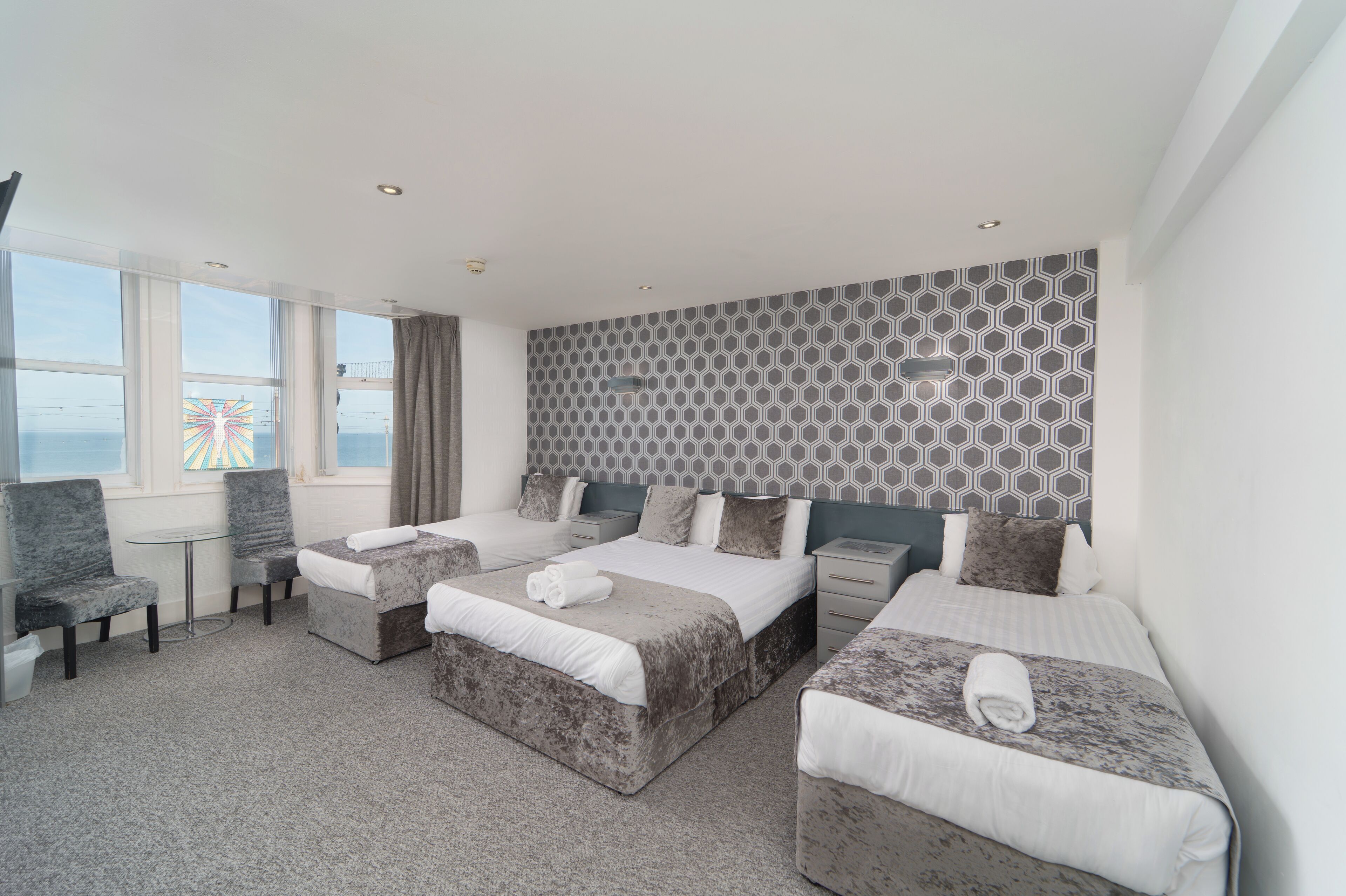 A hotel room with two beds, a small table, and a chair.