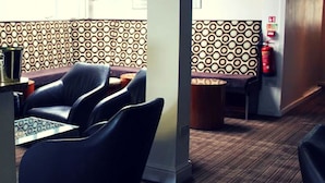 Een hotel lobby met een behang, een receptiebalie en een zithoek.