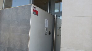 An elevator with a blue 'P' sign indicating parking, a fire alarm button, and a glass door. - Pension Don Claudio (Bilbao)
