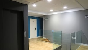 A modern interior with a wooden floor, a blue accent wall, and a glass partition. - Pension Don Claudio (Bilbao)