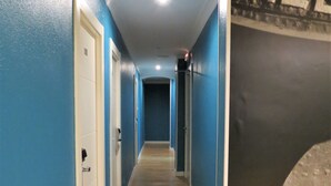 A hallway with blue walls and wooden flooring, leading to a door marked with the number 110. - Pension Don Claudio (Bilbao)