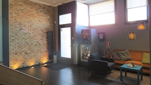 A lobby with a brick wall, a vending machine, a sofa, and a coffee table. - Pension Don Claudio (Bilbao)