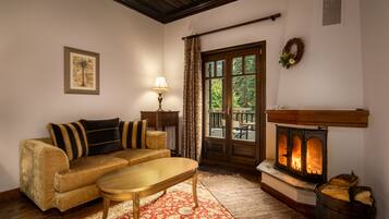 A cozy living room with a sofa, a wooden coffee table, a fireplace, and a view through a glass door.