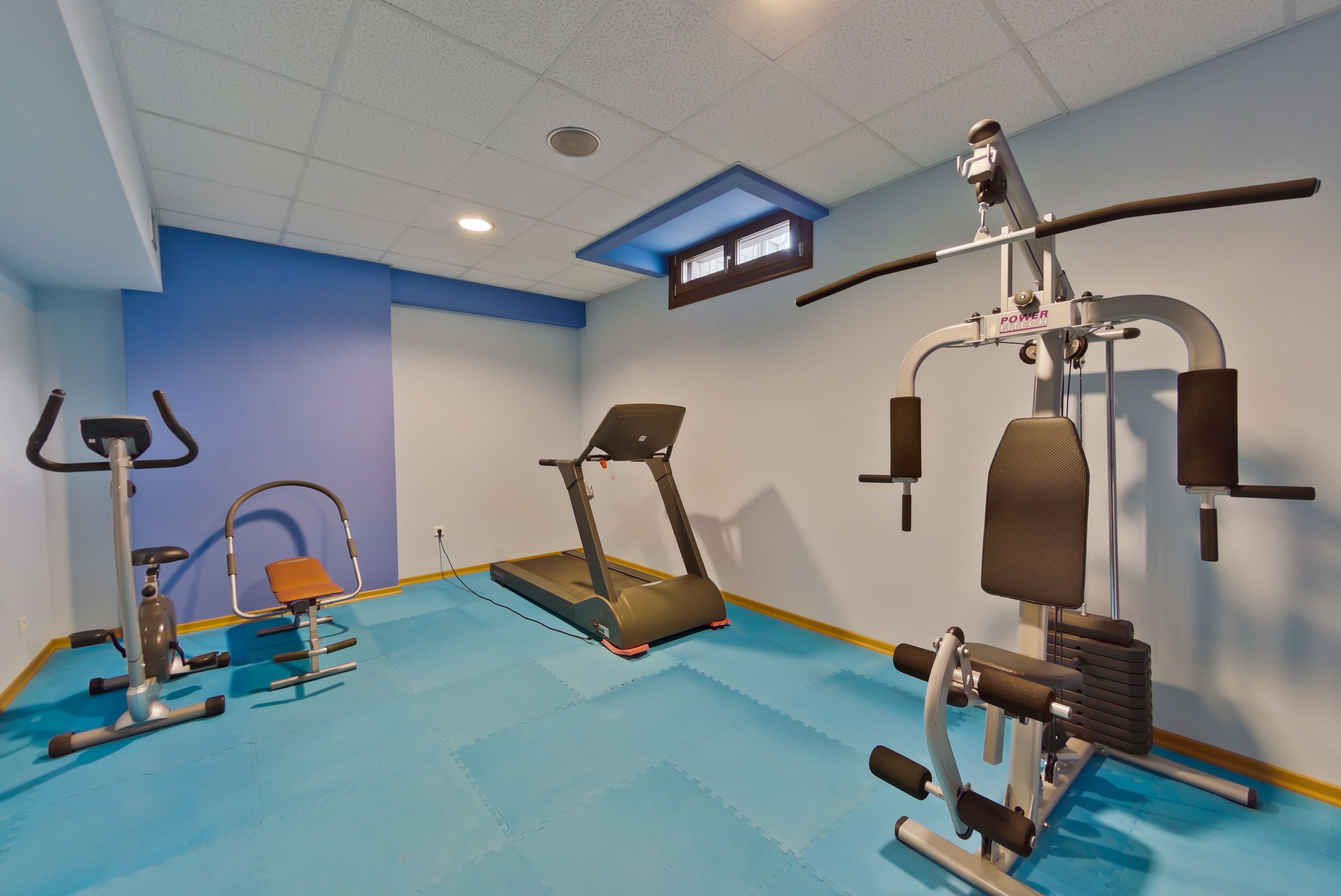 A gym with a treadmill, elliptical, and weight machines.